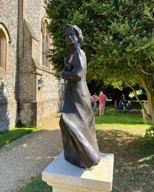 Photo of a statue of Jane Austen in front of St. Nicholas Church, Chawton